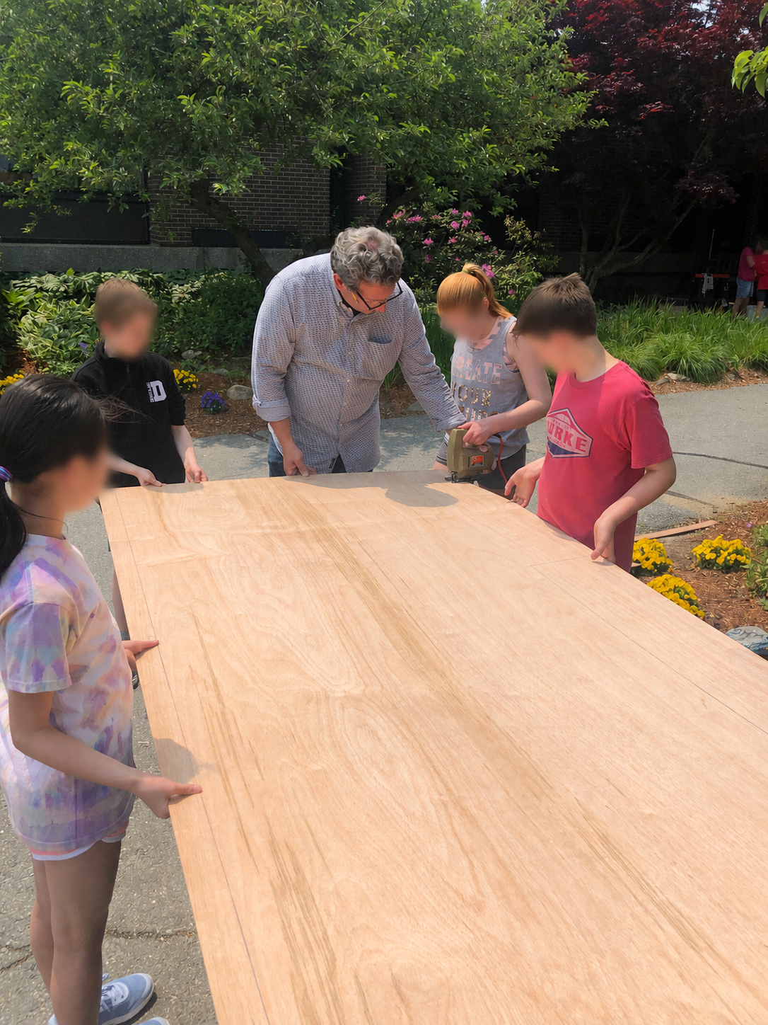A local carpenter teaching students how to safely cut plywood